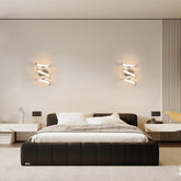 Modern bedroom with a black upholstered bed and wall lights.